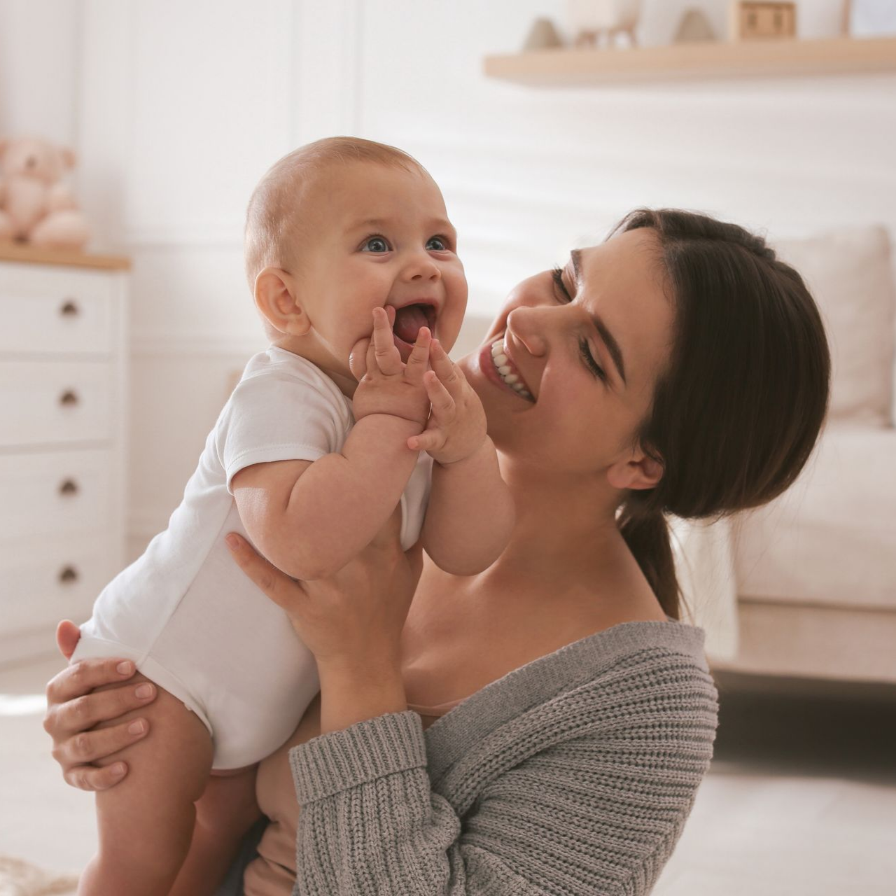 Une femme tient un bébé qui rit et lui sourit.