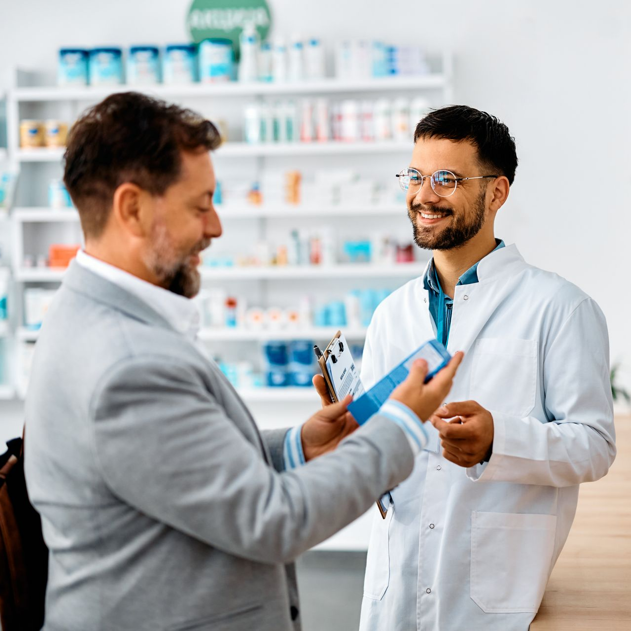 Un pharmacien qui conseille un client tenant un produit pharmaceutique.