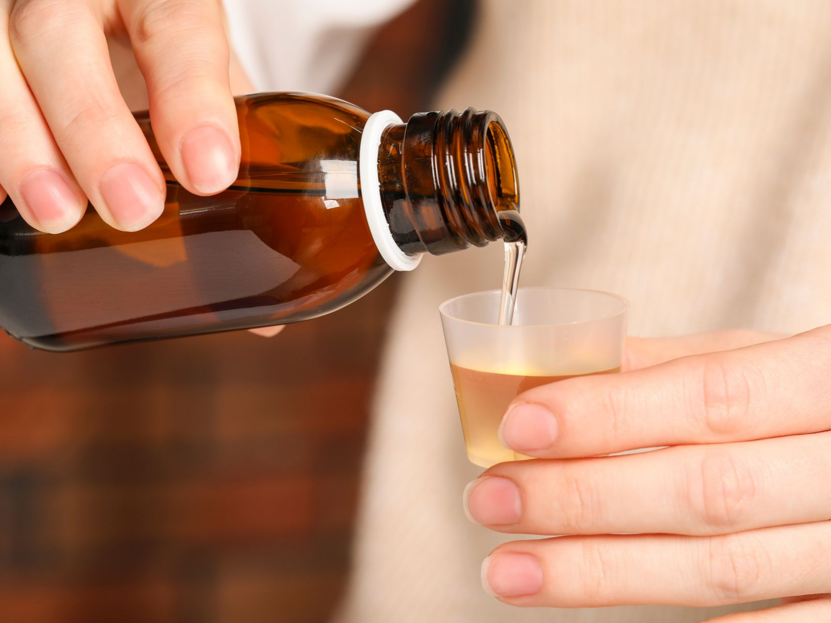 Une personne versant du sirop dans un petit gobelet.