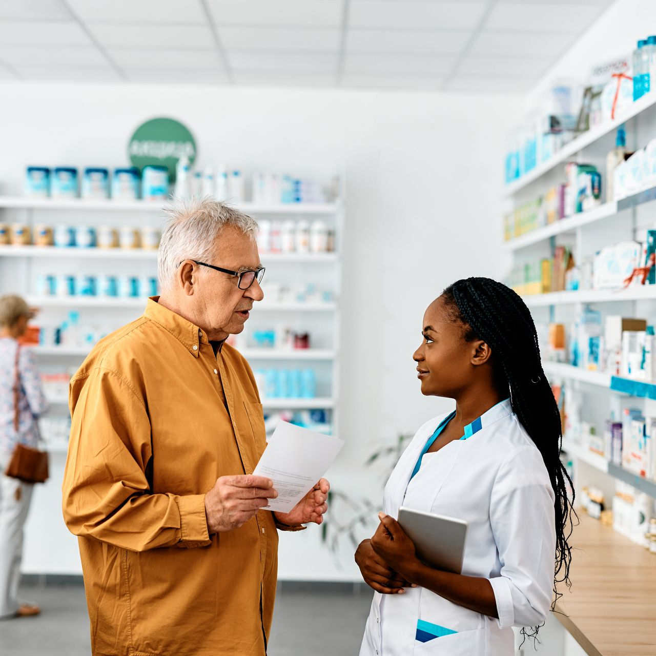 Une pharmacienne s'adresse à un client dans une pharmacie.