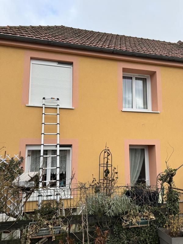 Maison au crépi jaune avec des volants roulants solaires dont l'un est fermé