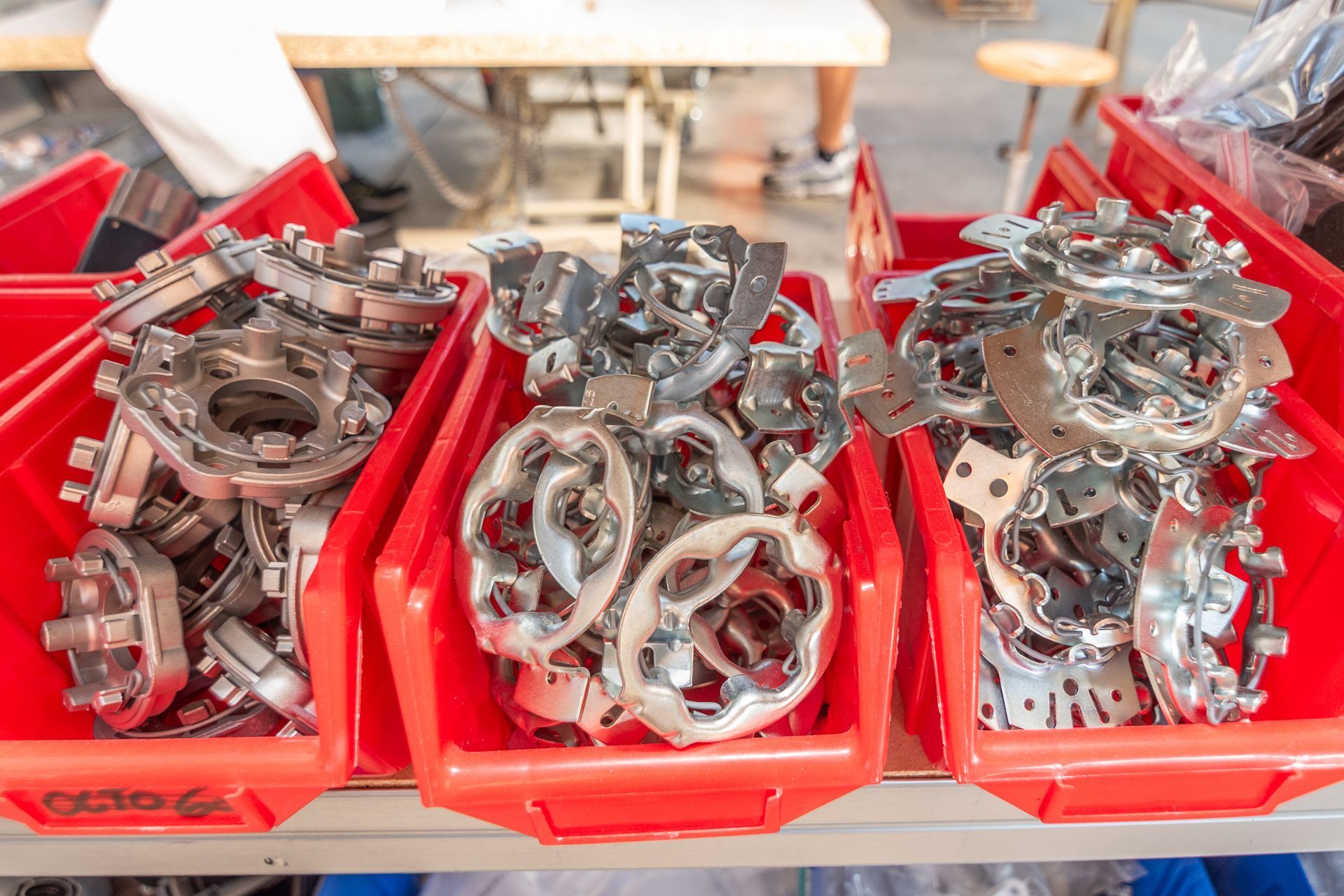 Bacs rouges remplis de pièces métalliques destinées à la fabrication ou à la réparation d'équipements manuels ou motorisés.