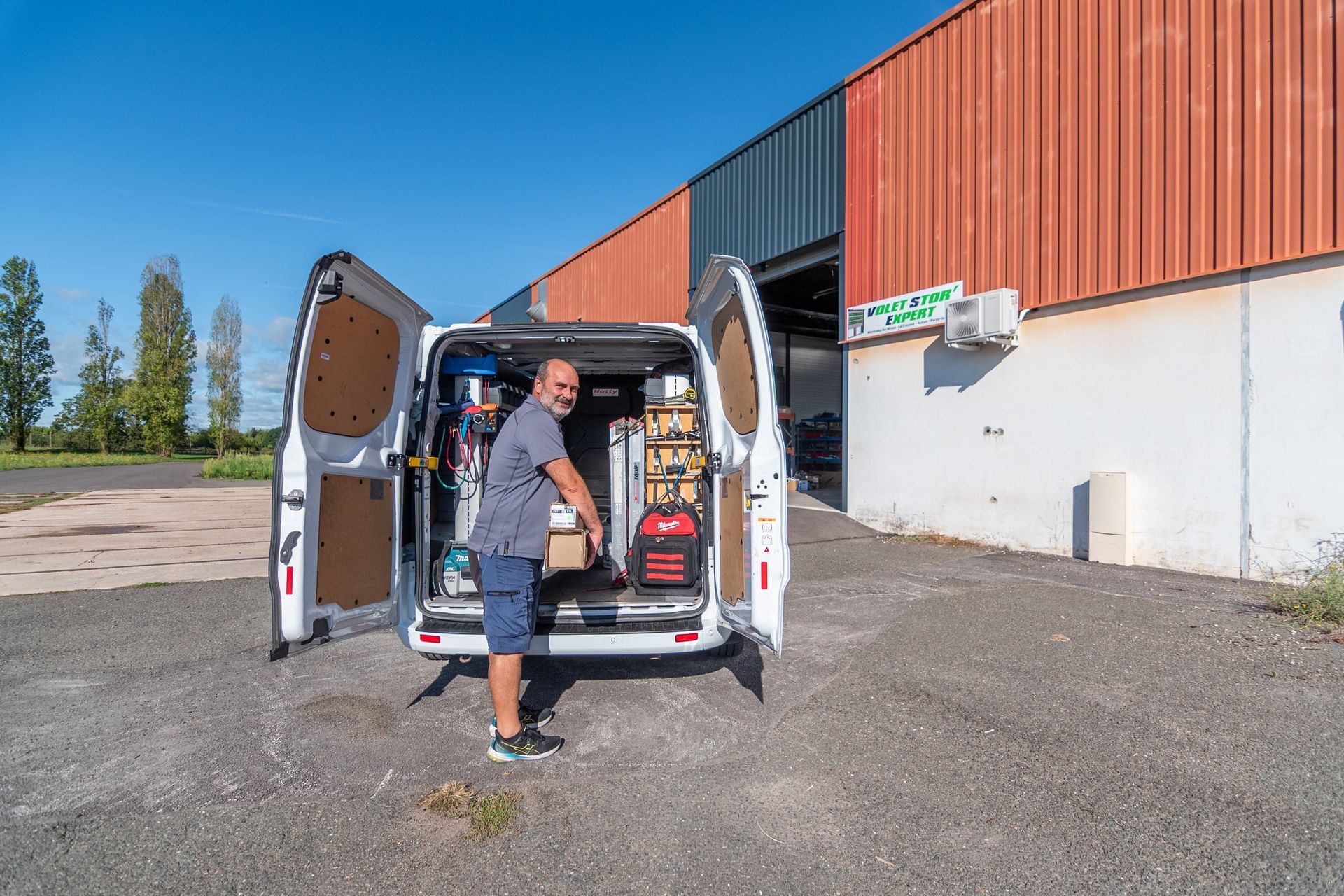 Un homme chargeant des outils à l'extérieur d'une camionnette.