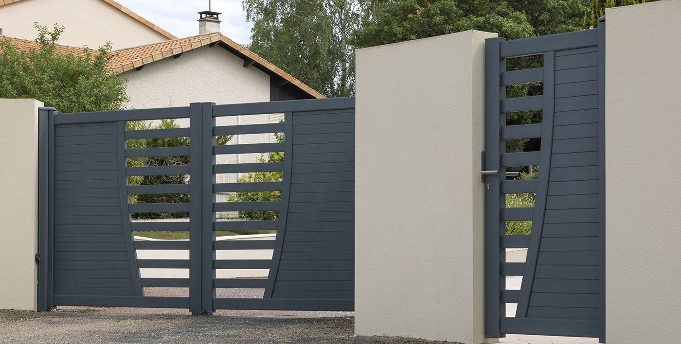 Gros plan sur un portail battant en aluminium de couleur anthracite devant une maison
