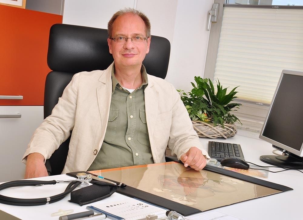 Ein Mann sitzt an einem Schreibtisch vor einem Computer.