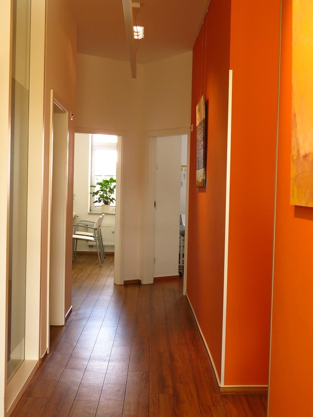 Ein langer Flur mit orangefarbenen Wänden und Holzböden