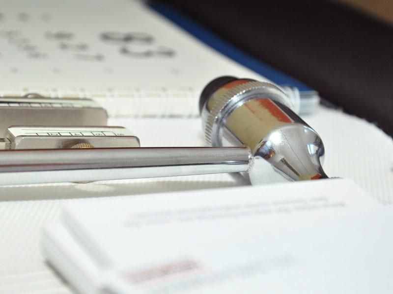 Ein Stift liegt auf einer Visitenkarte auf einem Klemmbrett