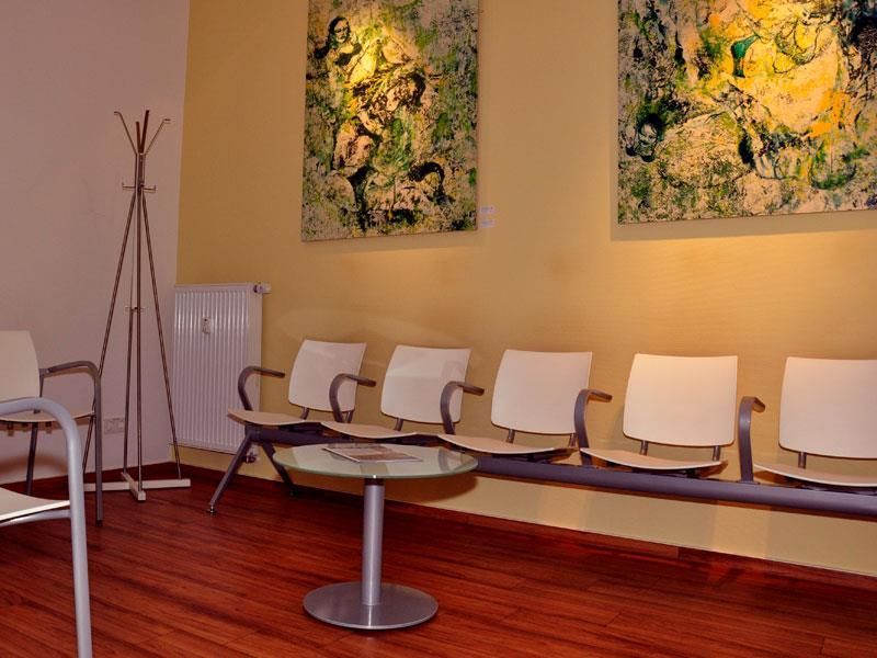 Ein Wartezimmer mit Stühlen und Gemälden an der Wand