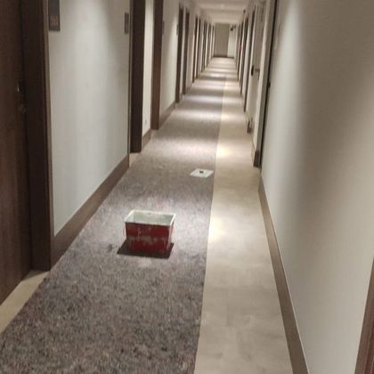 Pasillo de hotel con alfombra y una caja roja y blanca en el suelo.
