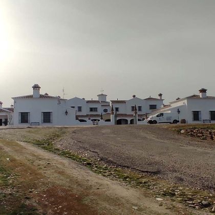 Hilera de casas blancas en un camino de grava bajo un cielo nublado.