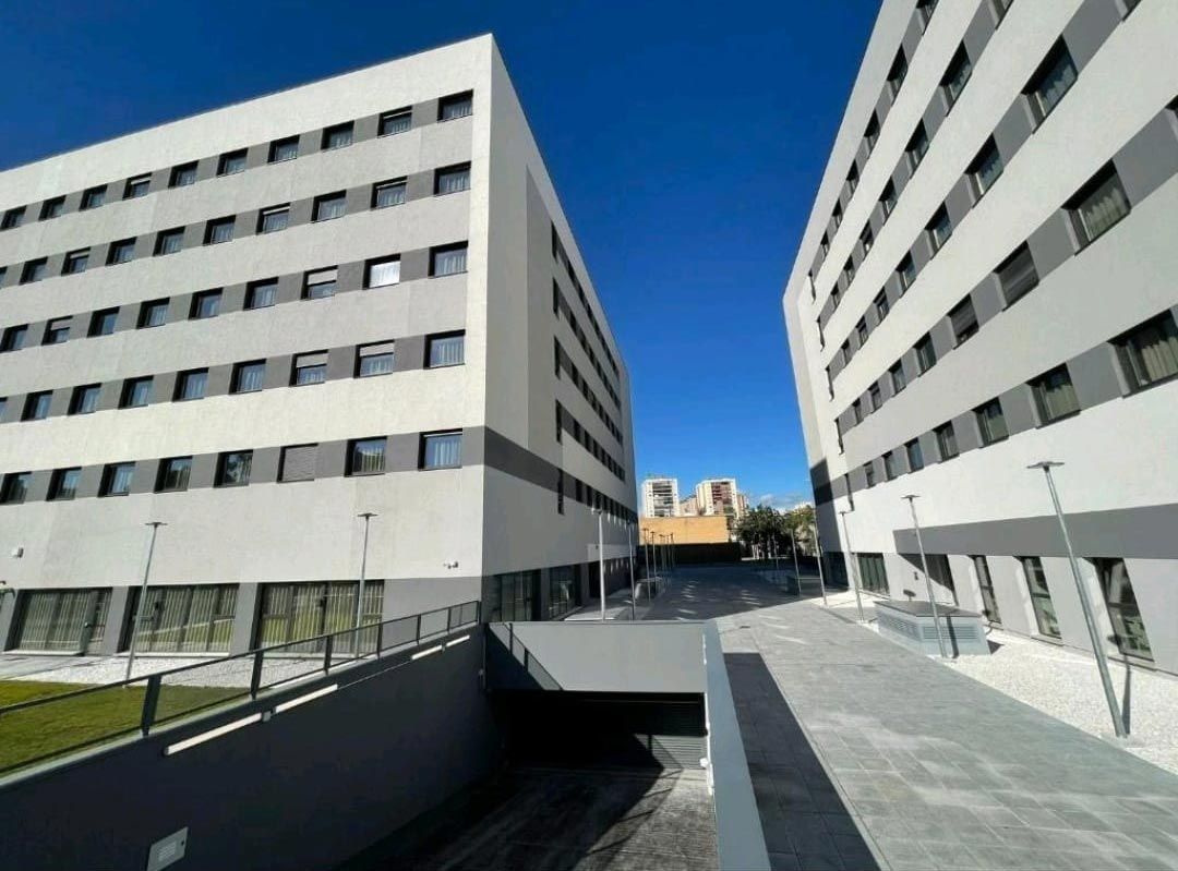 Edificios de apartamentos modernos que enmarcan un patio pavimentado bajo un cielo azul despejado.