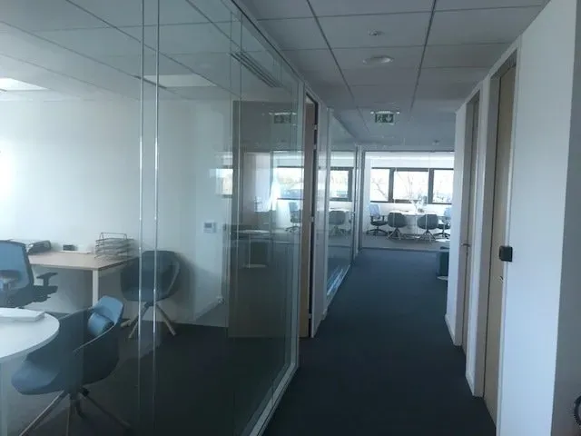 Long couloir avec des chaises derrière une vitre à gauche