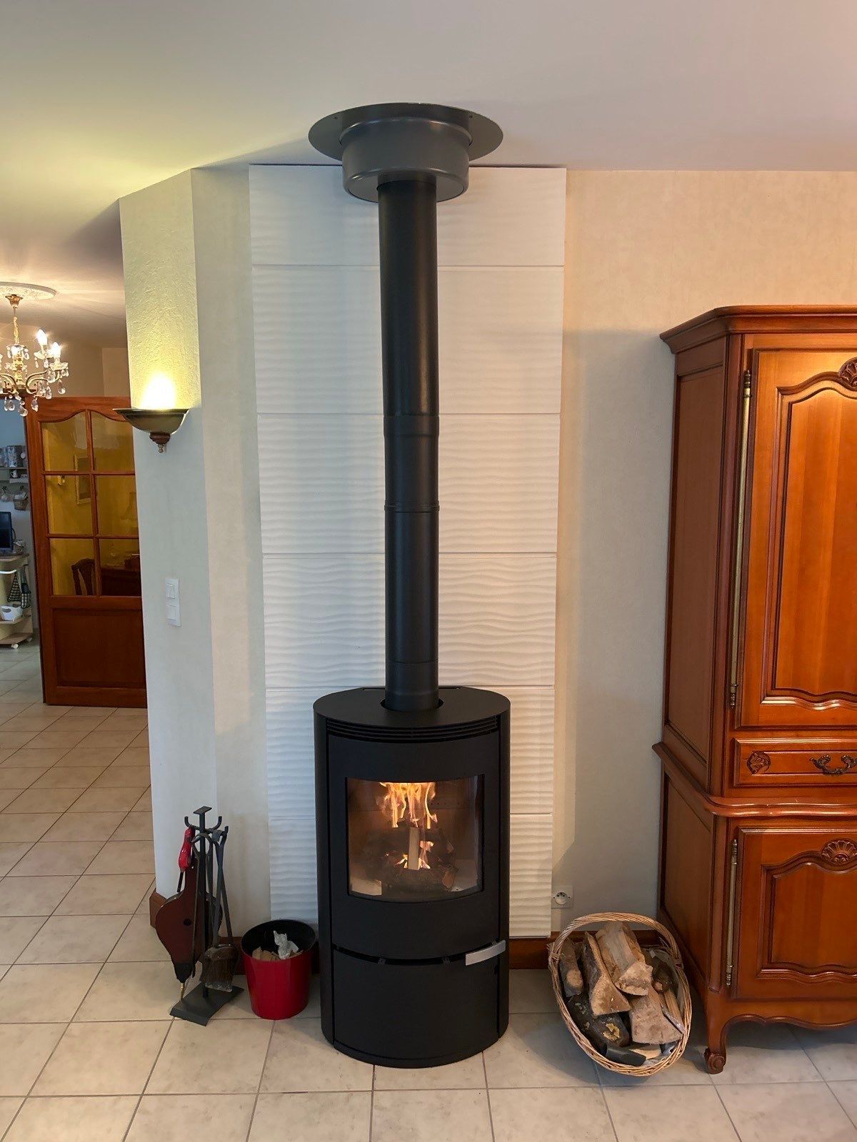 Un poêle à bois dans un salon avec un mur en pierre de parement blanche. 