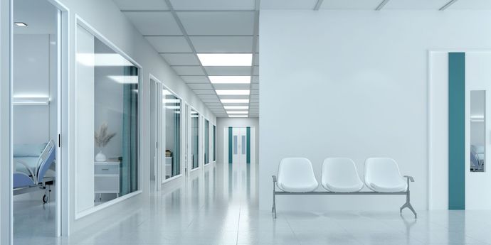 Ein langer Flur in einem Krankenhaus mit einer Bank in der Mitte.