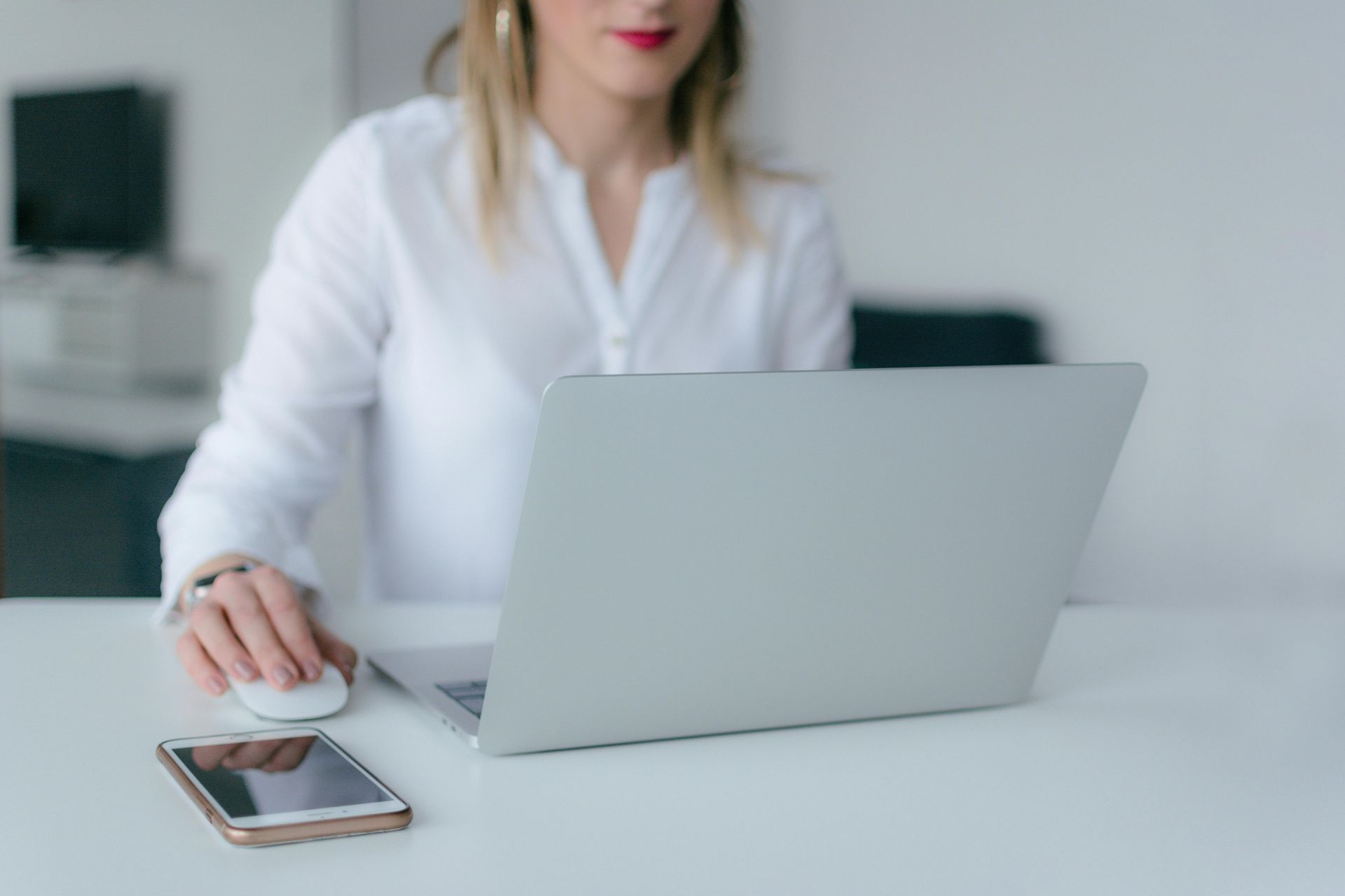 Eine Frau sitzt an einem Schreibtisch und benutzt einen Laptop.