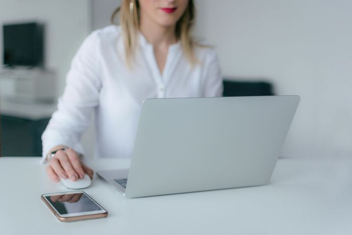 Eine Frau sitzt an einem Schreibtisch und benutzt einen Laptop.