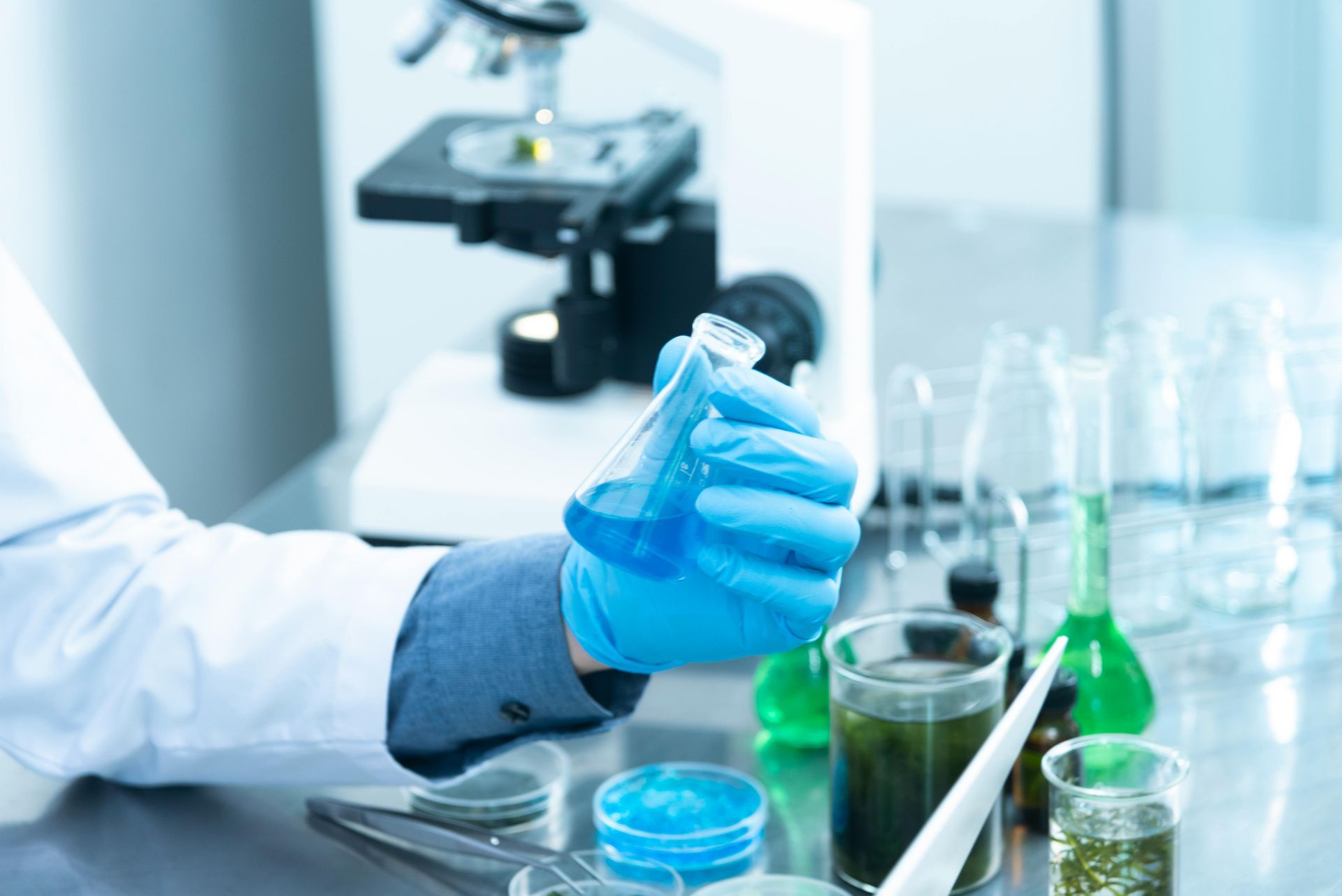 Ein Wissenschaftler hält in einem Labor einen Becher mit Flüssigkeit in der Hand.