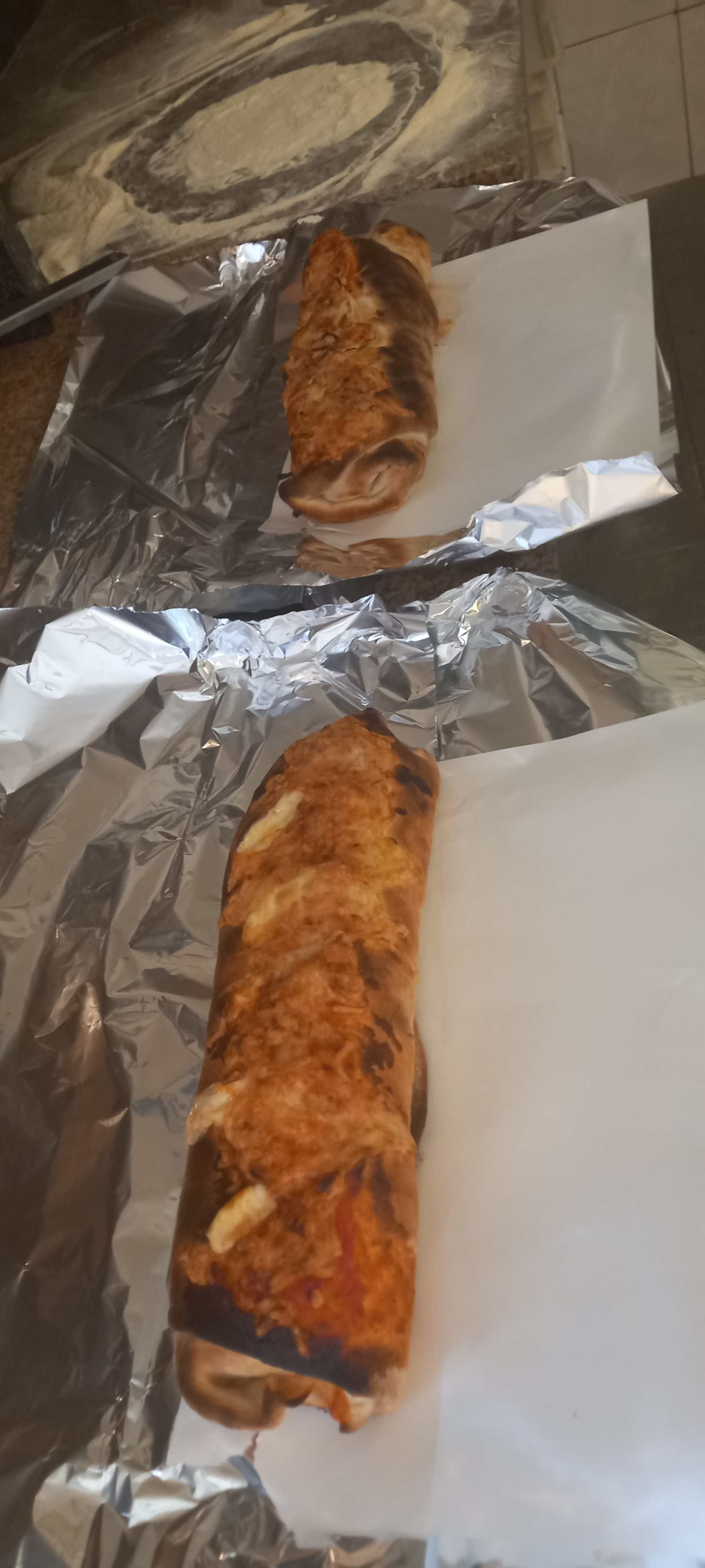 Eine Nahaufnahme eines in Alufolie eingewickelten Sandwiches auf einem Tisch.