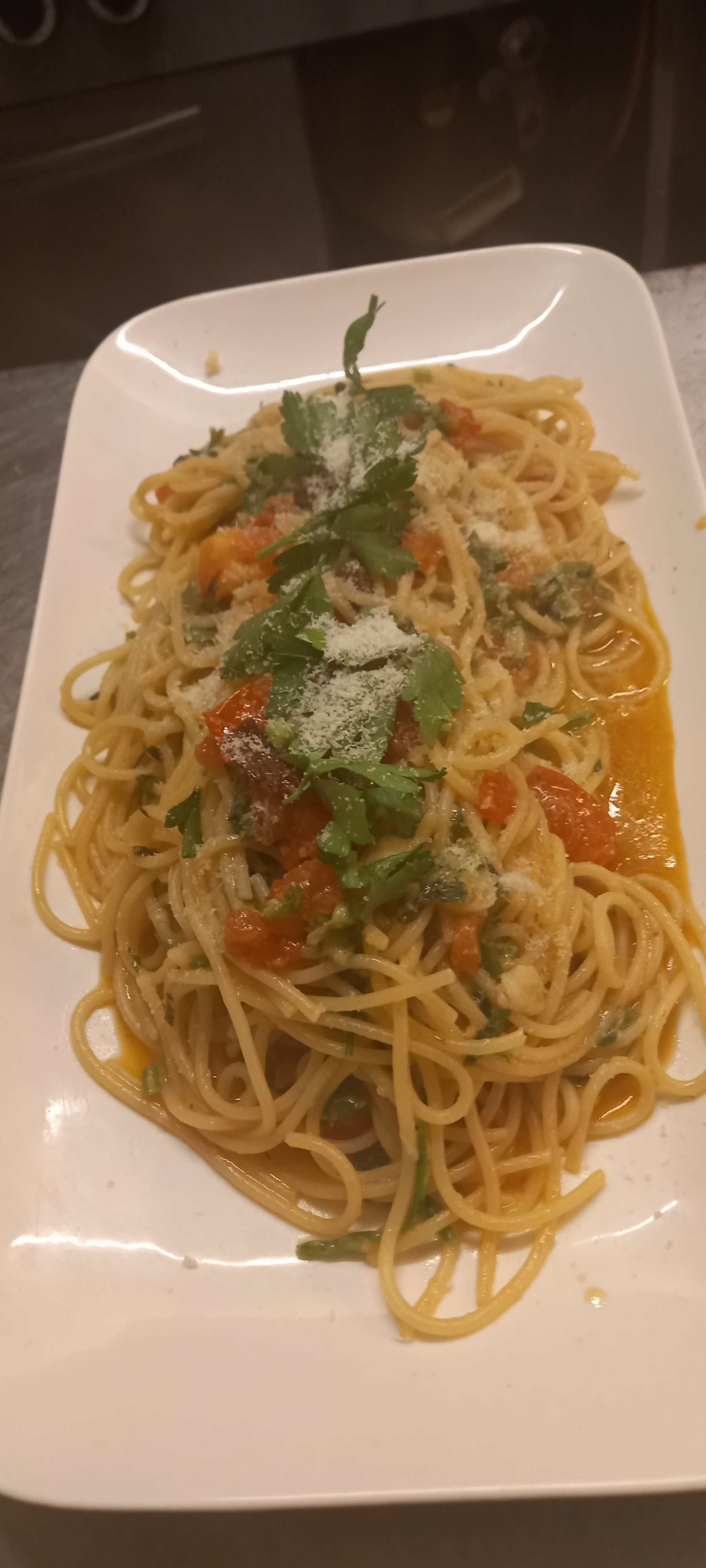 Ein weißer Teller mit Spaghetti und Tomaten auf einem Tisch. Leonardo Intelisano Pizzeria Dolce Vita