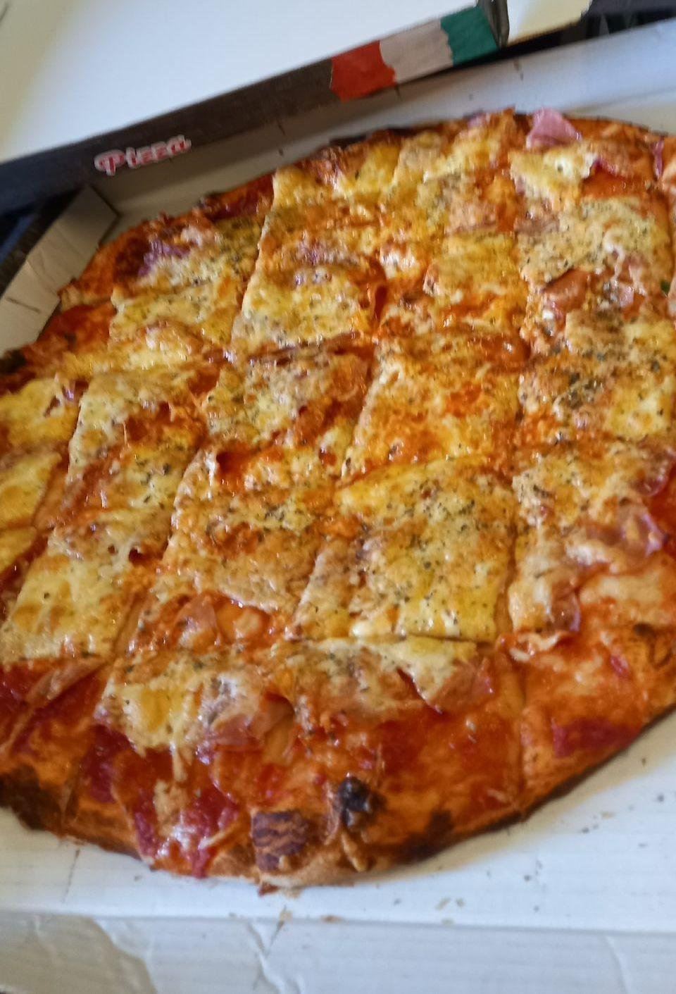 Auf einem Tisch steht eine Pizza in einem Pappkarton. Leonardo Intelisano Pizzeria Dolce Vita