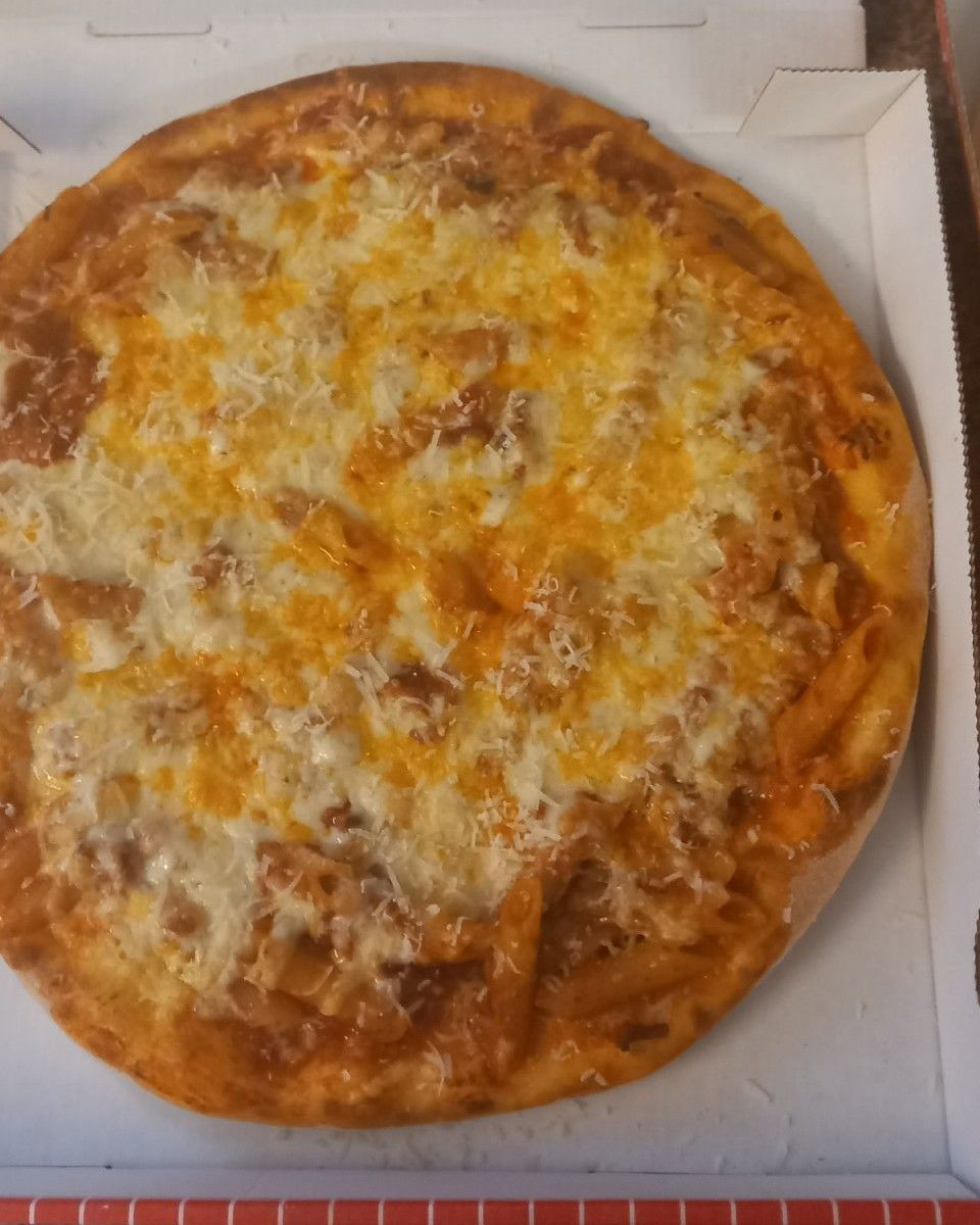 Auf einem Tisch steht eine Pizza in einem Pappkarton. Leonardo Intelisano Pizzeria Dolce Vita