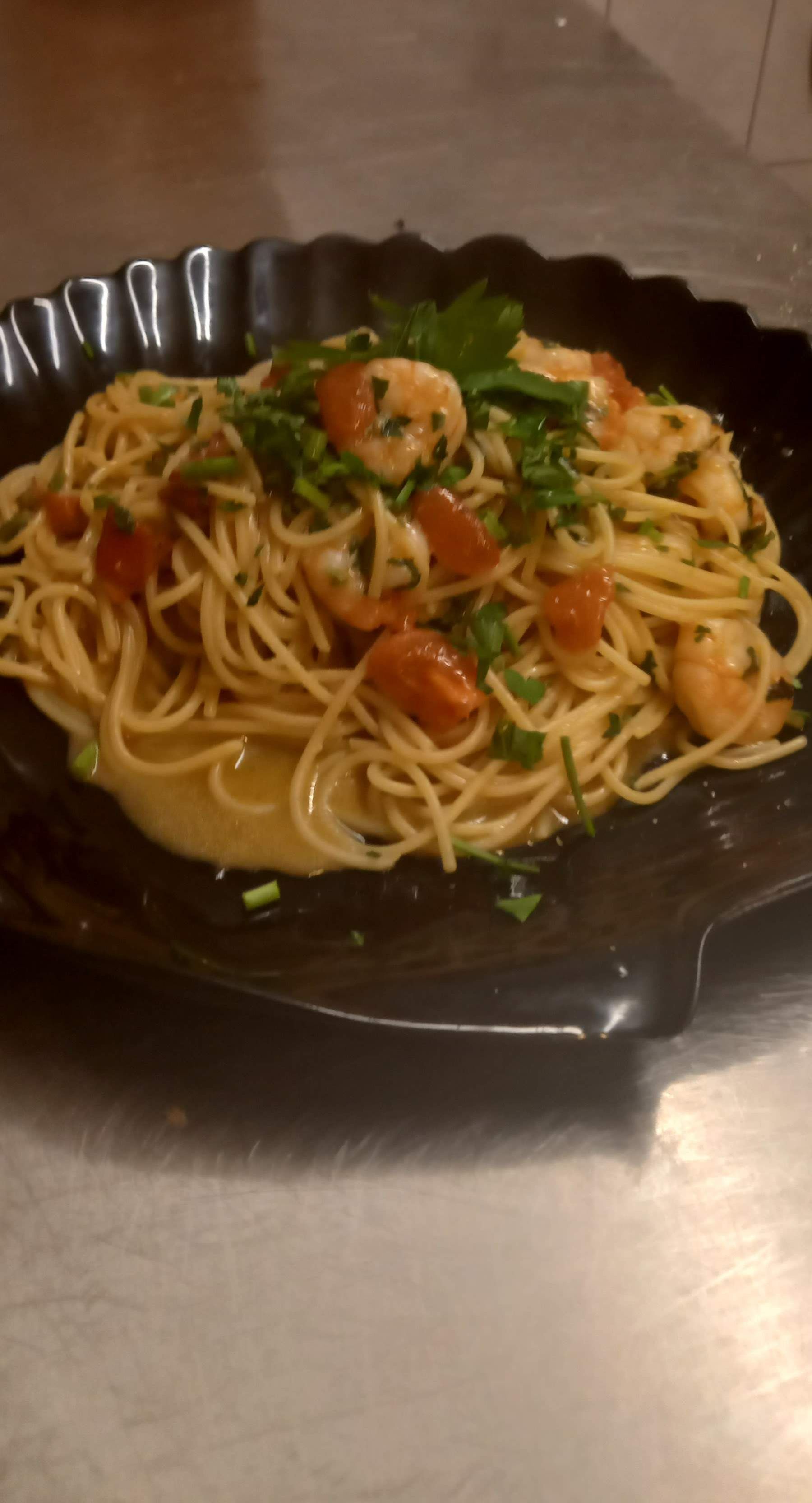 Ein Teller Spaghetti mit Garnelen und Petersilie auf einem Tisch