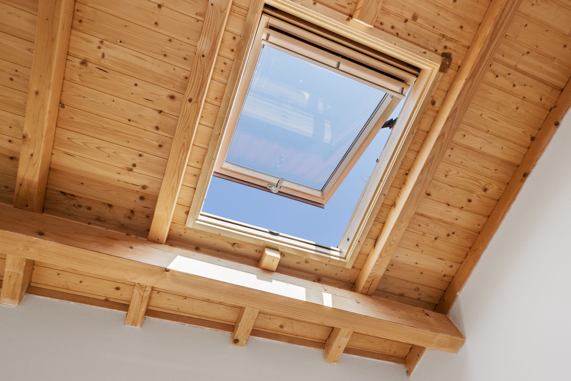 Puits de lumière ouvert dans le plafond en bois, révélant le ciel bleu.