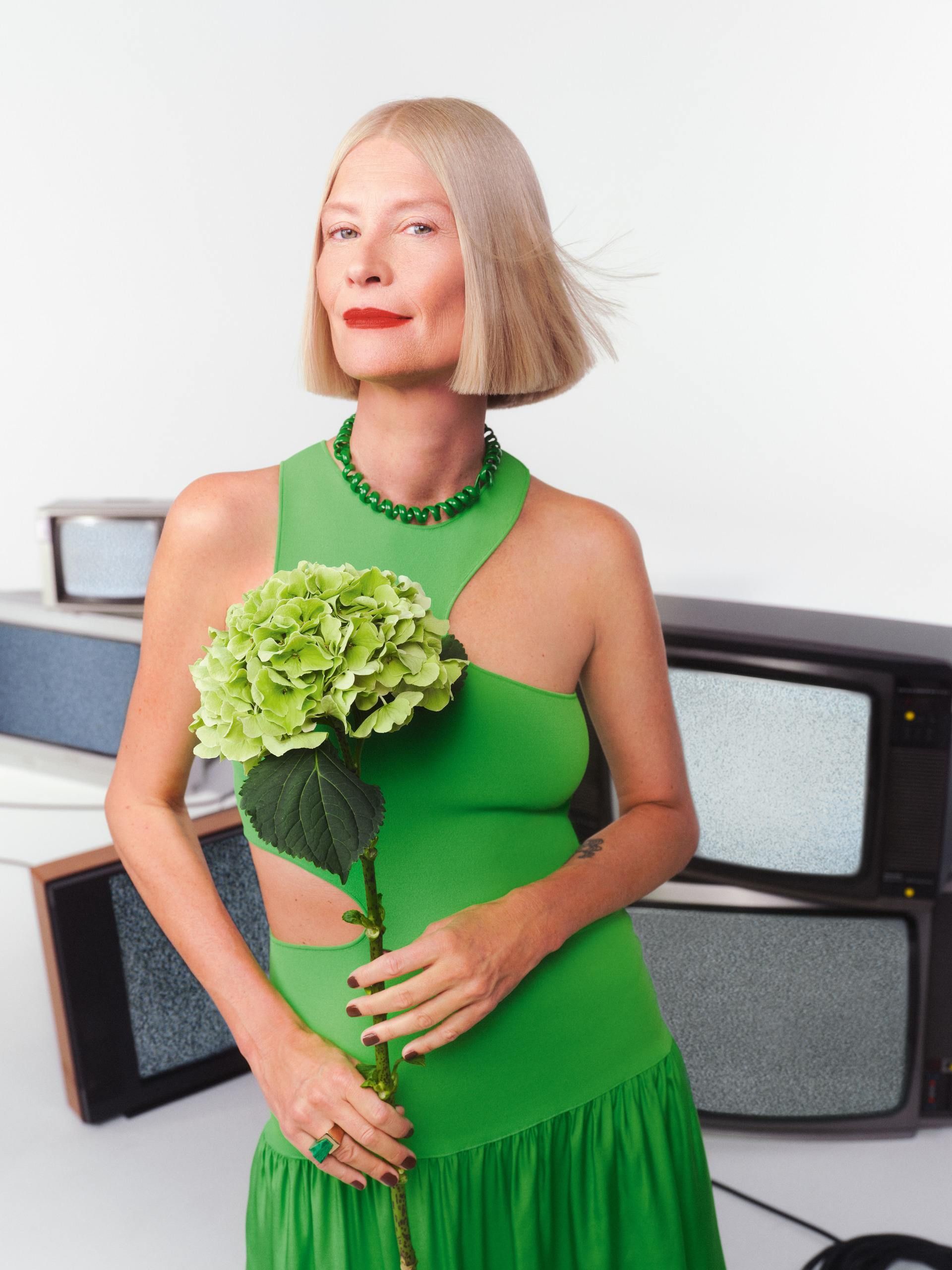 Dame mit blondem Bob und auffällig rot geschminkte Lippen trägt ein grünes Kleid