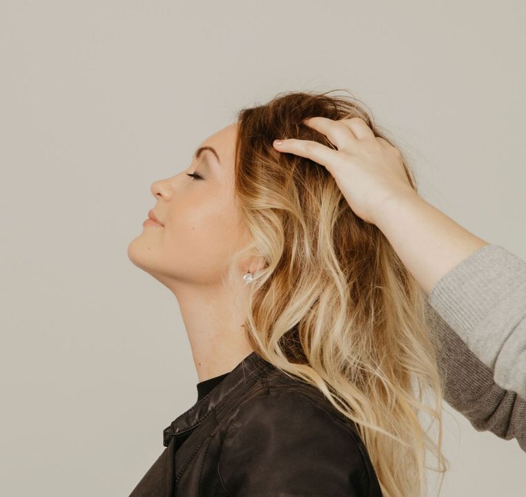 Kopfmassage bei einer Frau mit blondierten Haaren