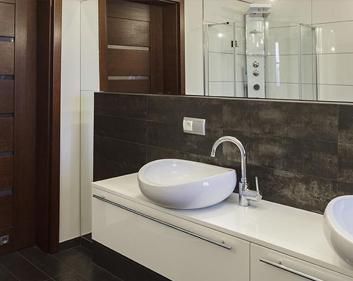 Un baño con dos lavabos y un espejo grande.