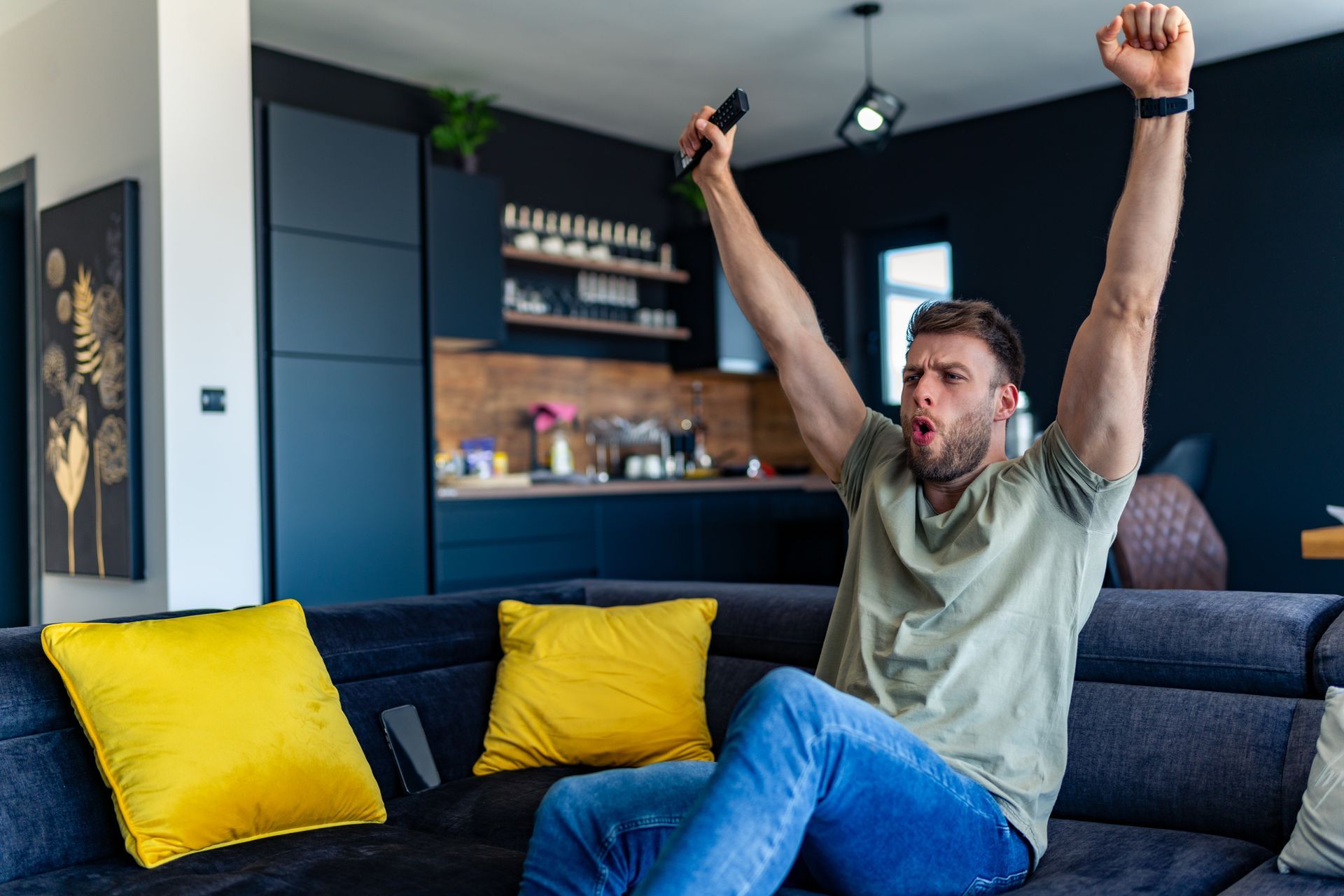 Jeune homme exultant devant son téléviseur
