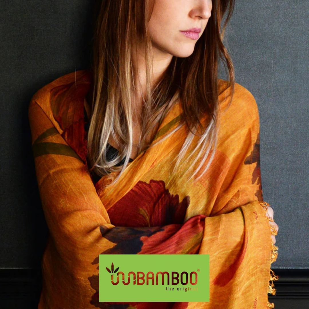 Giovane donna a mezzo busto, capelli lunghi castano chiaro, avvolta in un foulard arancione con motivi floreali. in basso il logo di Inbamboo