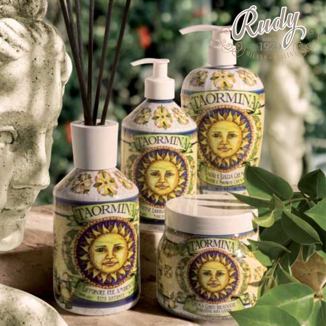 Quattro prodotti da bagno Rudy Profumi a tema Taormina con illustrazioni di volti baciati dal sole, tra cui un diffusore, due erogatori a pompetta e un vasetto di crema.