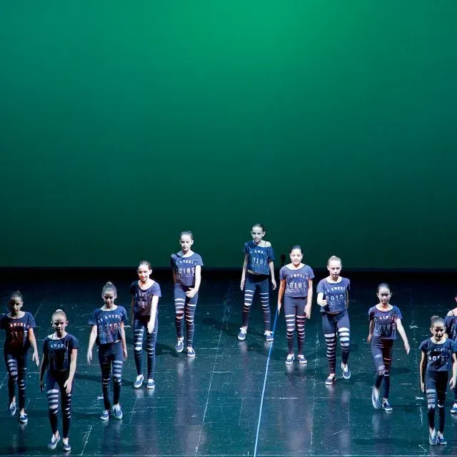 Un grup de persones ballant en un escenari amb un fons verd