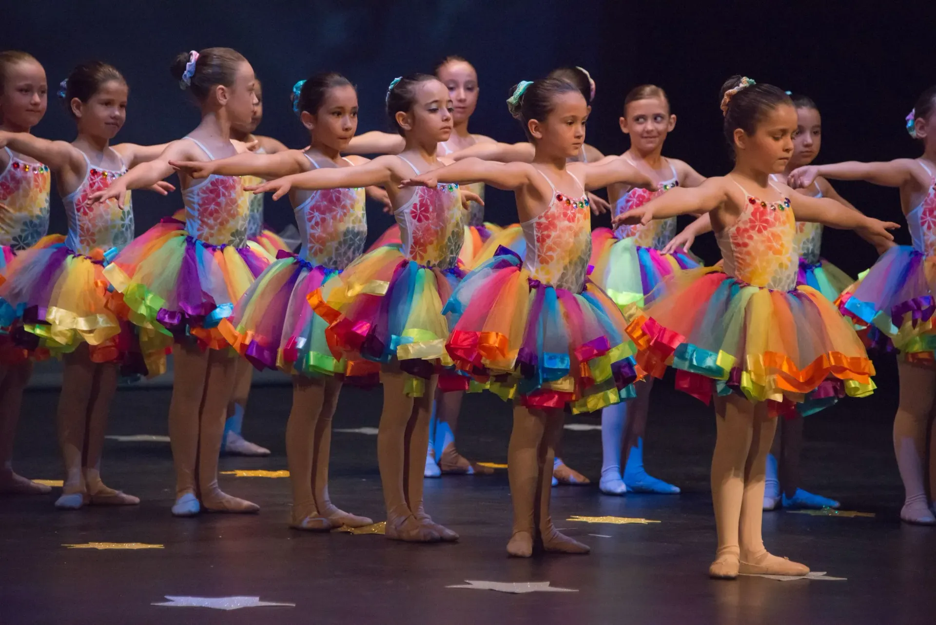 Un grup de noies joves amb tutús de colors ballen en un escenari