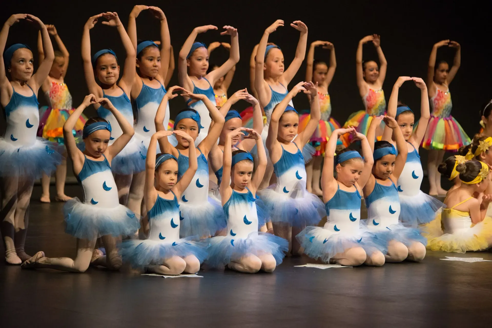 Un grup de noies joves amb tutús ballen en un escenari.