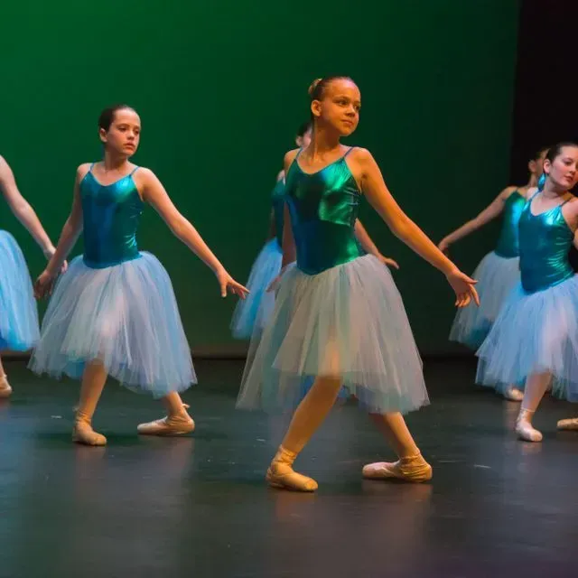 Un grup de noies joves amb tutús blaus i blancs ballen en un escenari