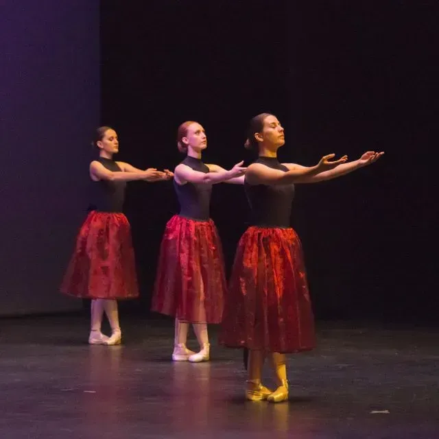 Tres dones amb faldilles vermelles ballen en un escenari
