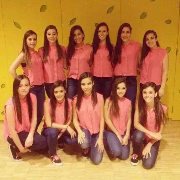 Un grup de noies posant per a una foto davant d'una paret groga