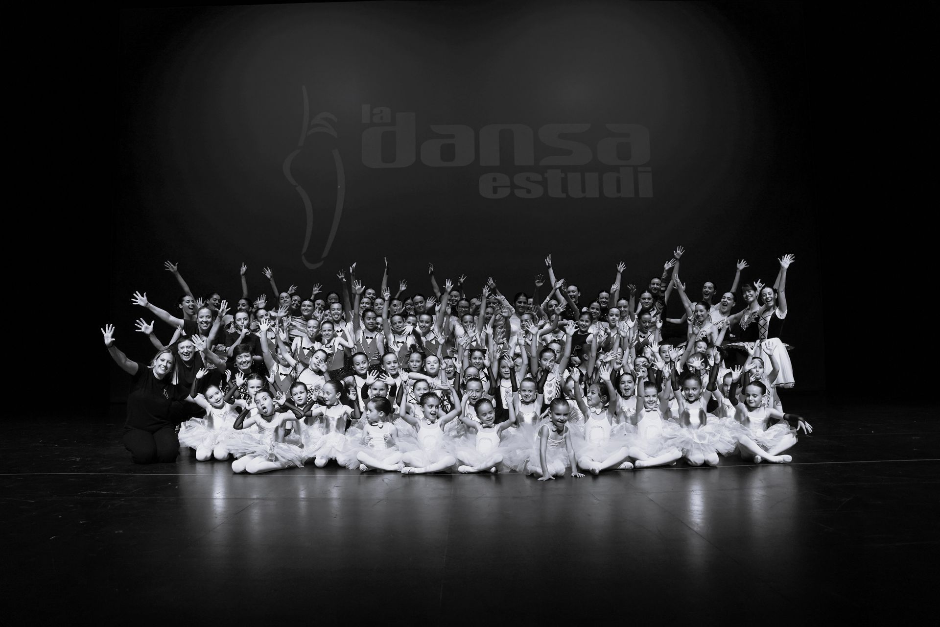 Un gran grup de persones ballant en un escenari en una foto en blanc i negre.