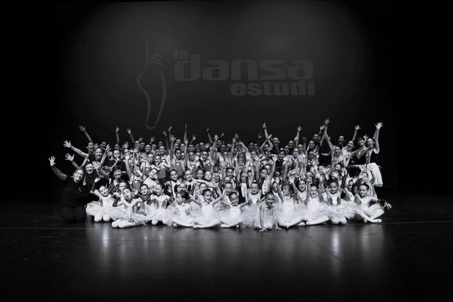 Un gran grup de persones ballant en un escenari en una foto en blanc i negre.