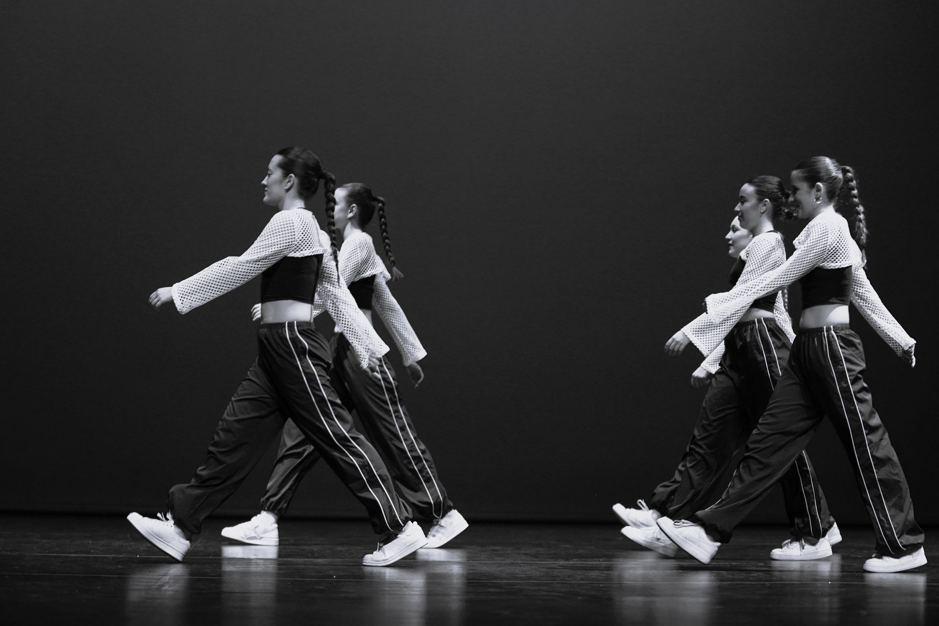 Un grupo de mujeres jóvenes bailan en un escenario en una fotografía en blanco y negro.