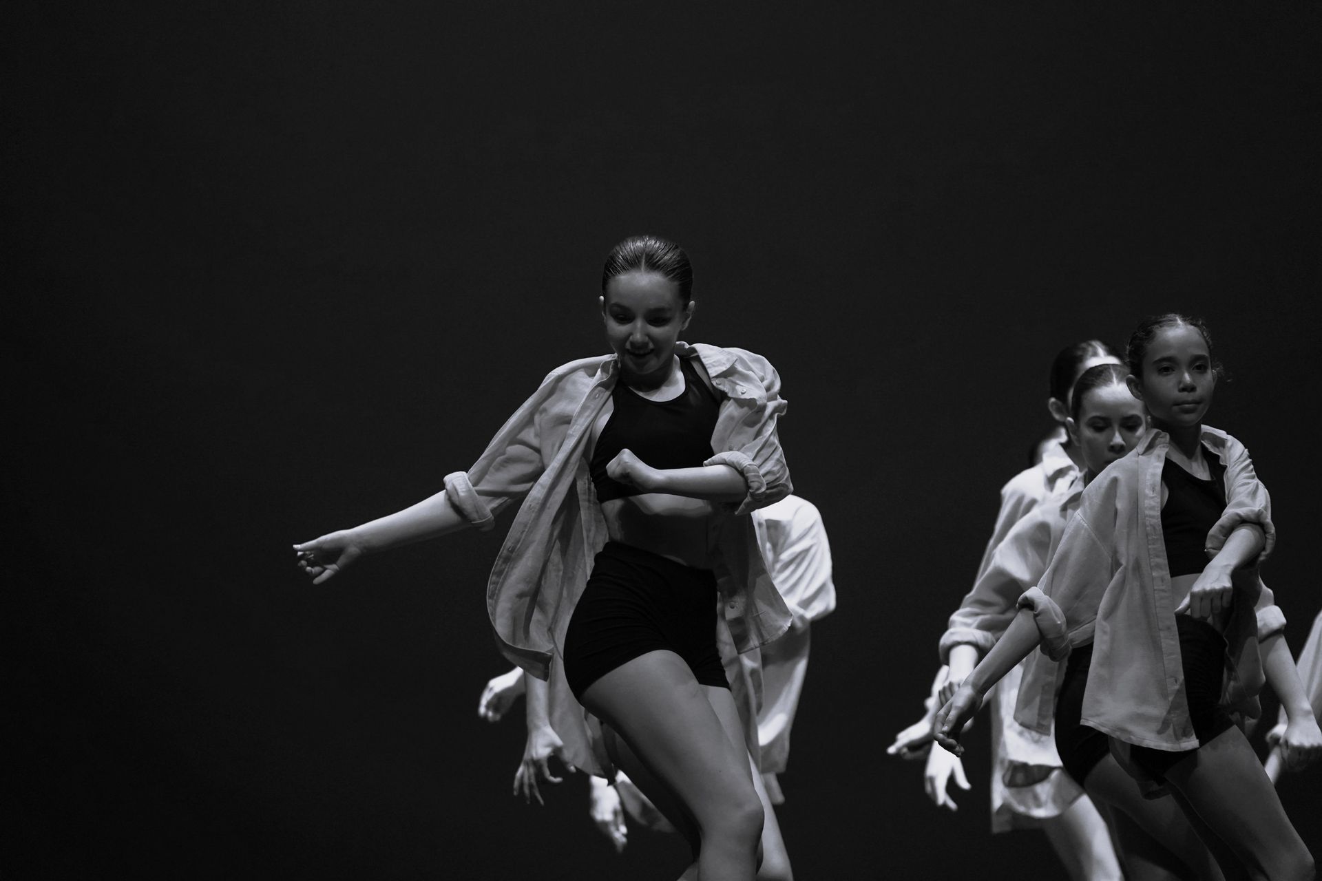 Un grupo de mujeres jóvenes bailan en un escenario en una fotografía en blanco y negro.