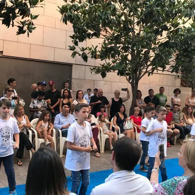 Un grup de persones està mirant un grup de nens actuar