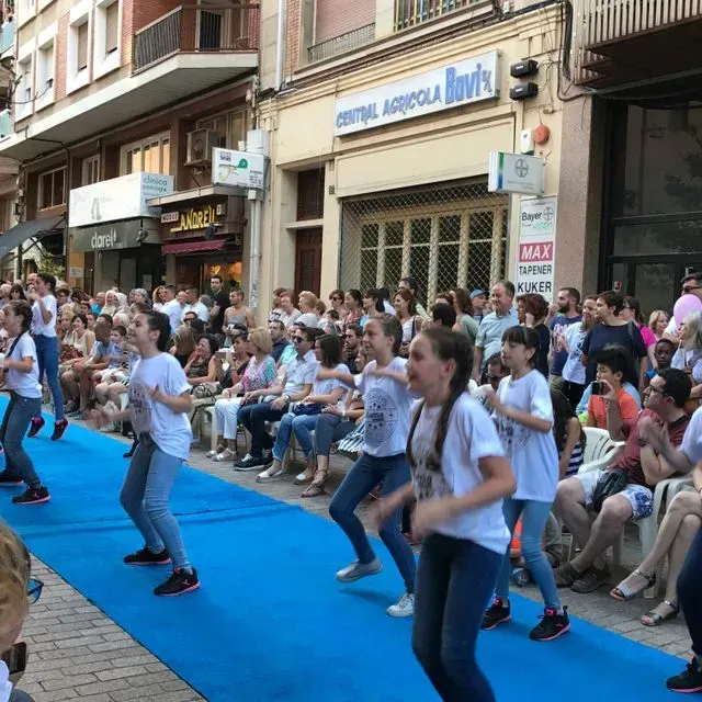 Un grup de persones balla davant d'un edifici que diu central agrícola