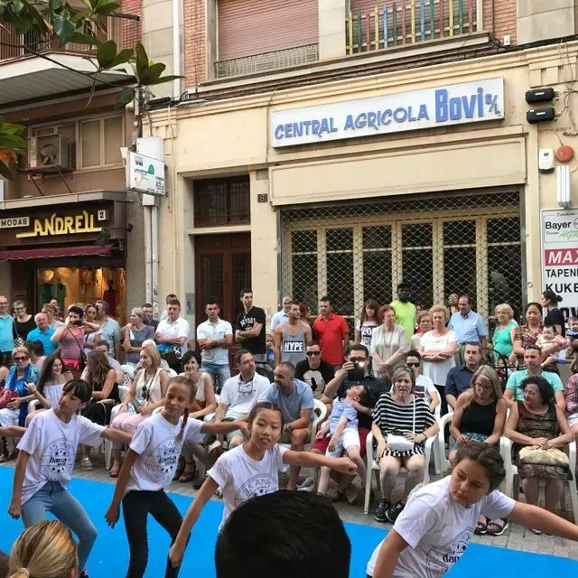 Un grup de persones balla davant d'un edifici que diu central agricola bovik