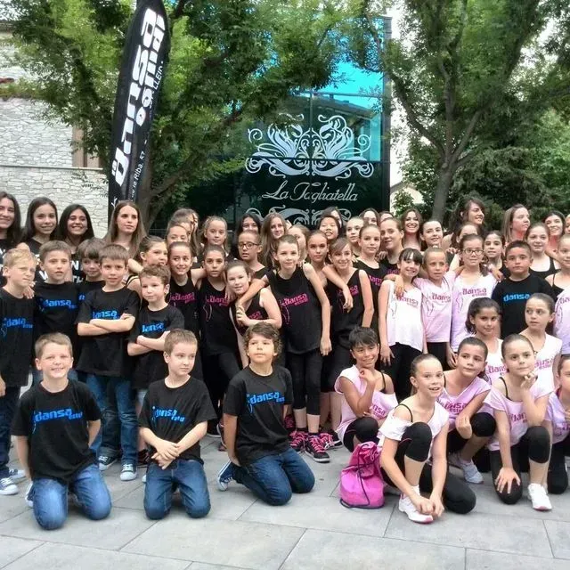 Un gran grup de nens posant per a una foto davant d'un rètol que diu la felicitat