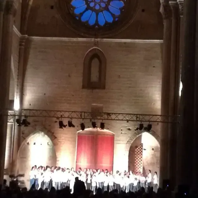 Un gran grup de persones estan dretes en un escenari d'una església