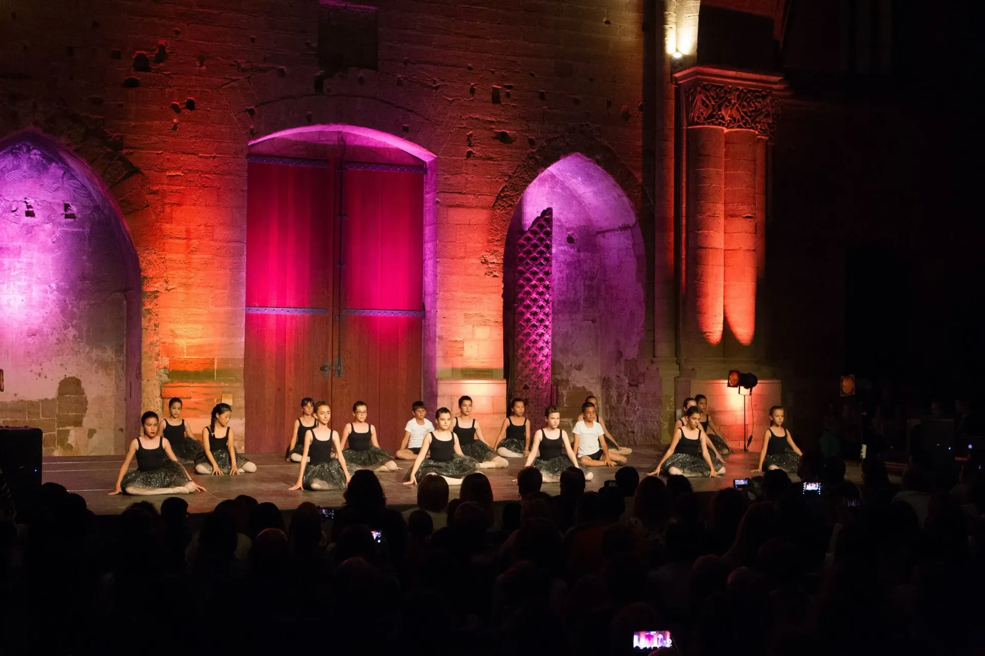 Un grup de dones balla en un escenari davant d'una multitud.