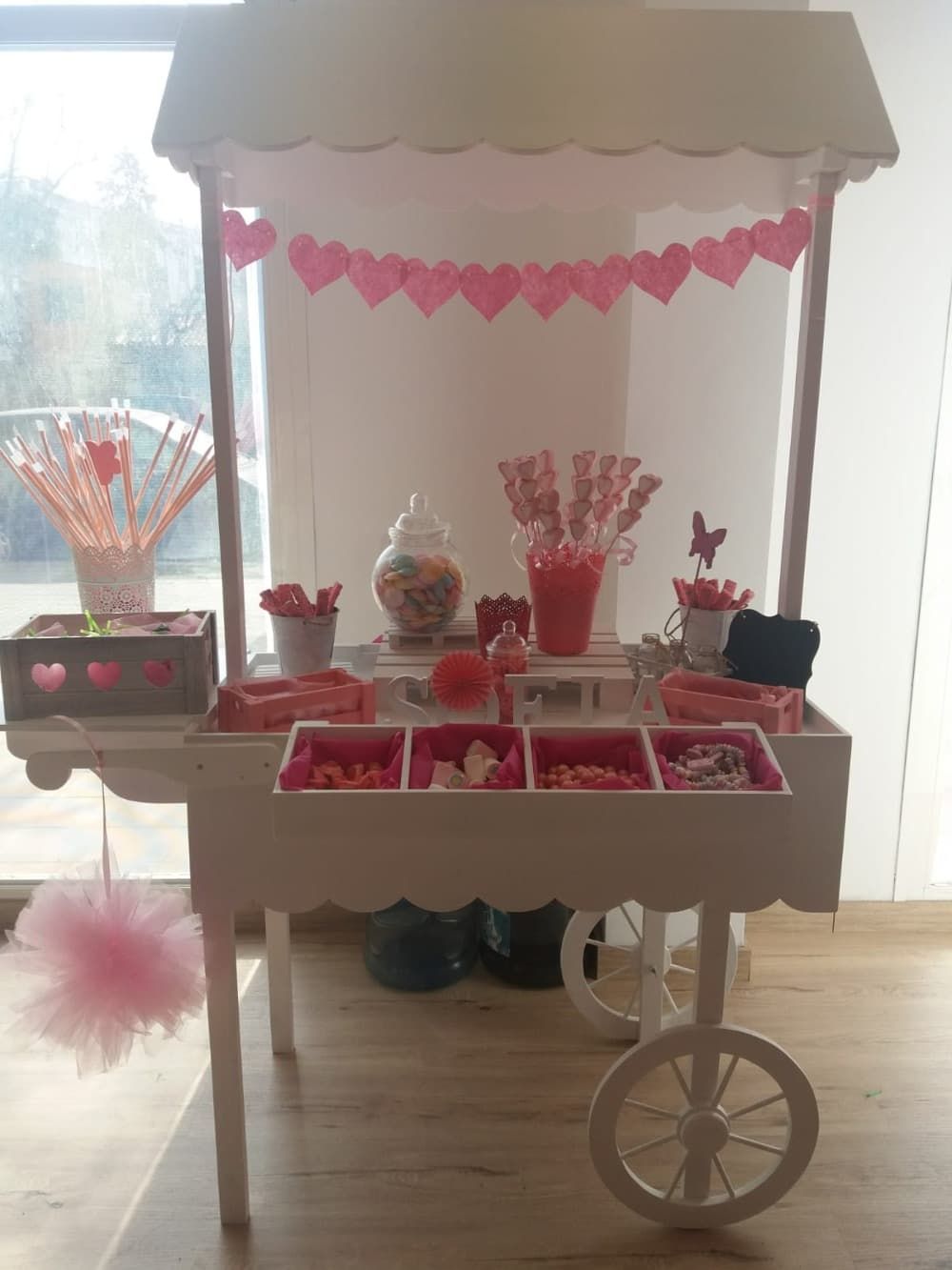 Un carrito de dulces con corazones rosados.